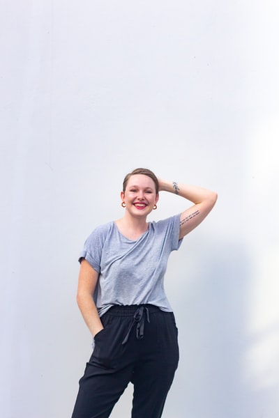 Dressed in a grey round collar T-shirt and a black skirt smiling woman
